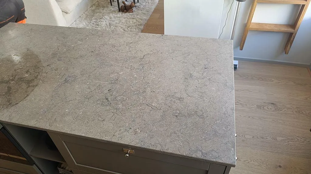 Detalj av bänkskiva i matt Azul Valverde marmor på grå köksö med trägolv i Göteborg.