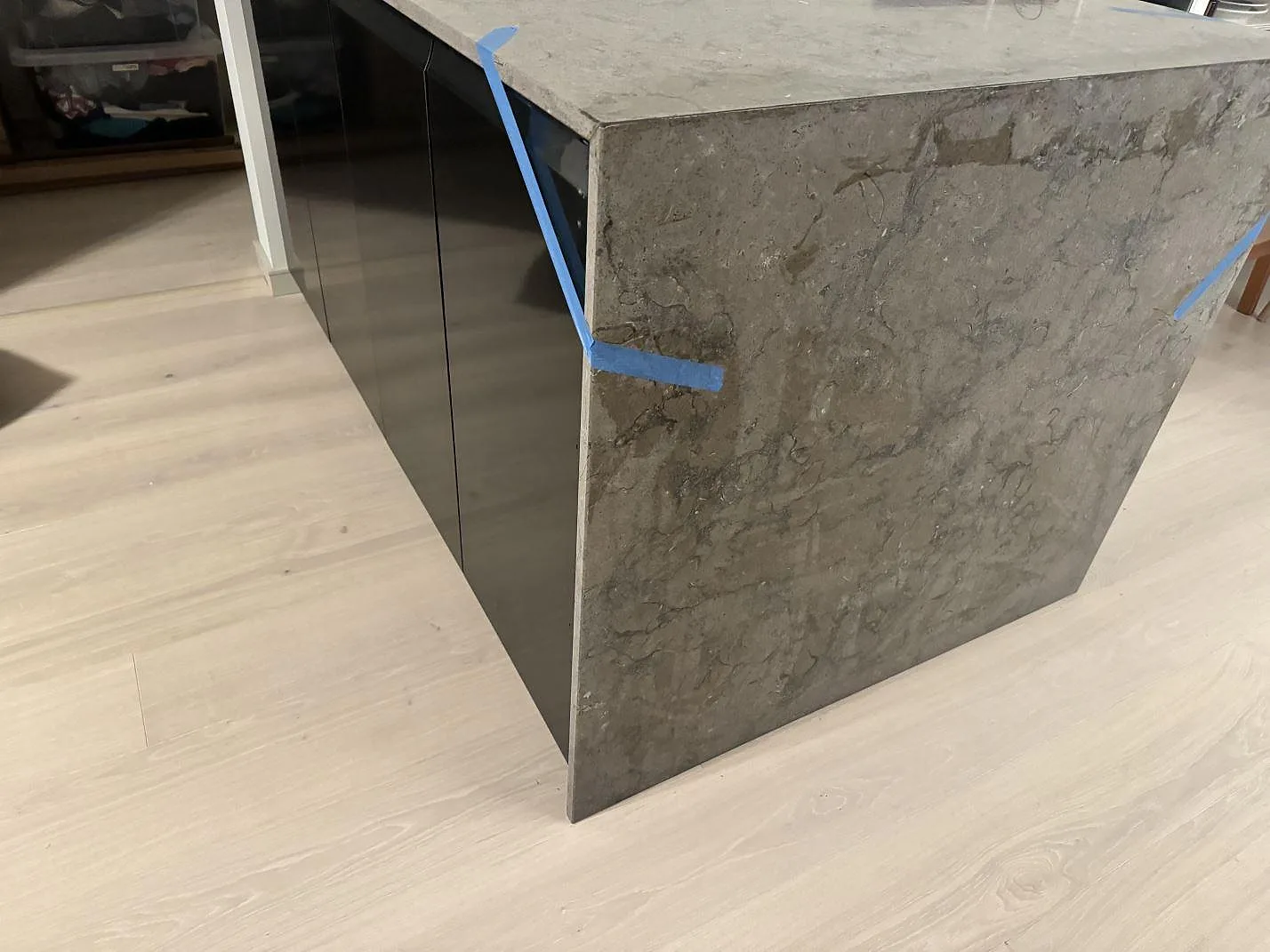 Närbild av vattenfallsida i grå Azul Valverde, matt marmorbänkskiva monterad på svart köksö i Göteborg.