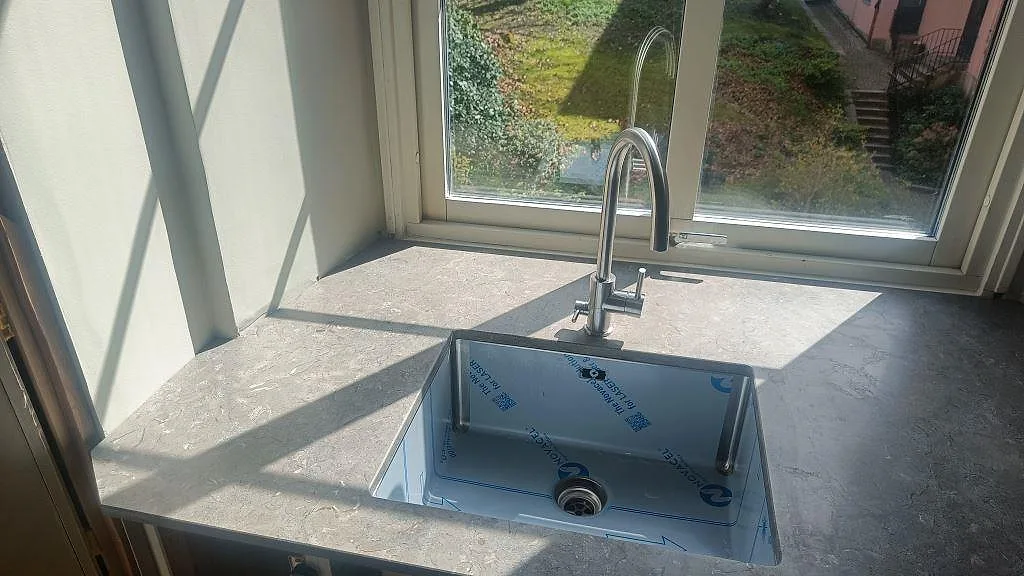 Närbild på matt Azul Valverde marmorbänkskiva med underlimmad diskho under ett fönster i Göteborg.