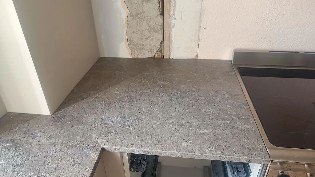 Matt Azul Valverde köksbänkskiva vid svart häll och beige köksstommar under montering i Göteborg.