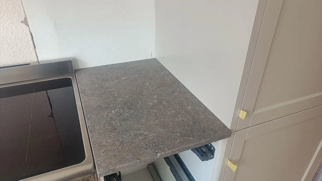 Detalj av Azul Valverde marmorbänkskiva, matt, bredvid svart häll och ljusa köksskåp i Göteborg.