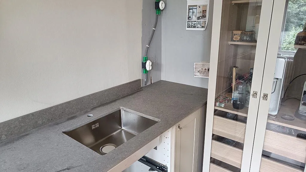 Köksbänkskiva i Azul Valverde marmor, matt, med diskho och låg stänkkant i ett kök i Göteborg.
