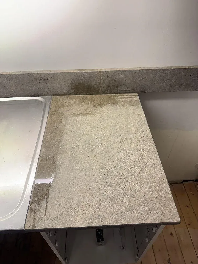 Sidovy av bänkskiva och stänkkant i matt Azul Valverde marmor längs väggsidan i Göteborg.