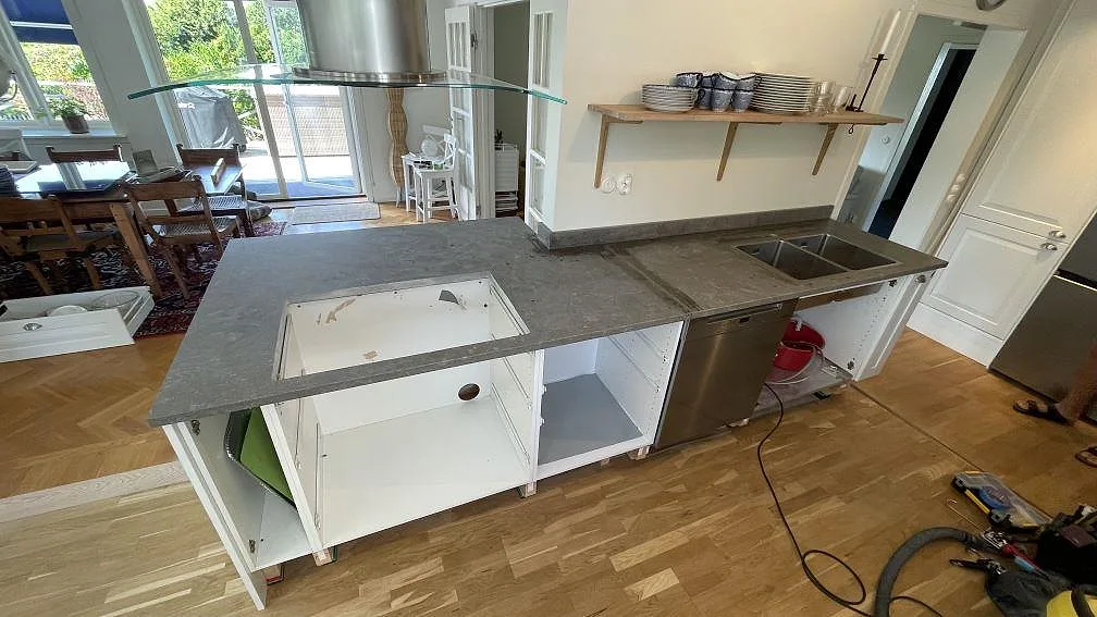 Köksbänkskiva i matt Azul Valverde marmor med stänkkant och öppna köksstommar under montering i Hovås.