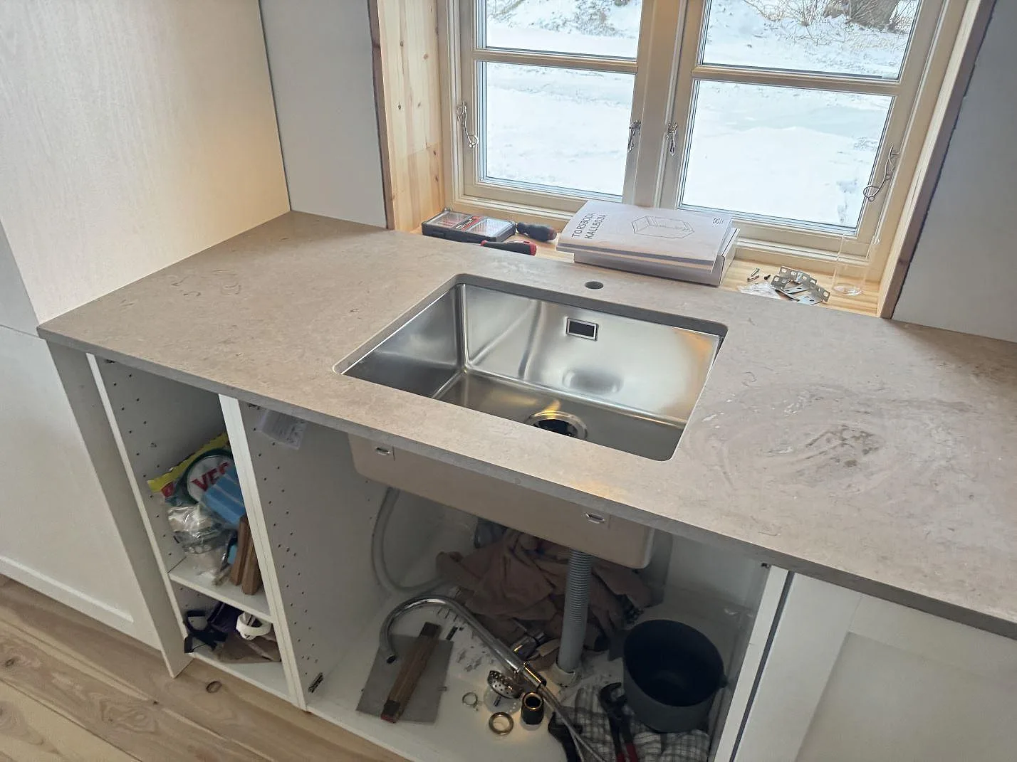 Köksbänkskiva i Azul Valverde, matt grå kalksten, med underlimmad rostfri diskho monterad under stenen i ett kök i Kristianstad.