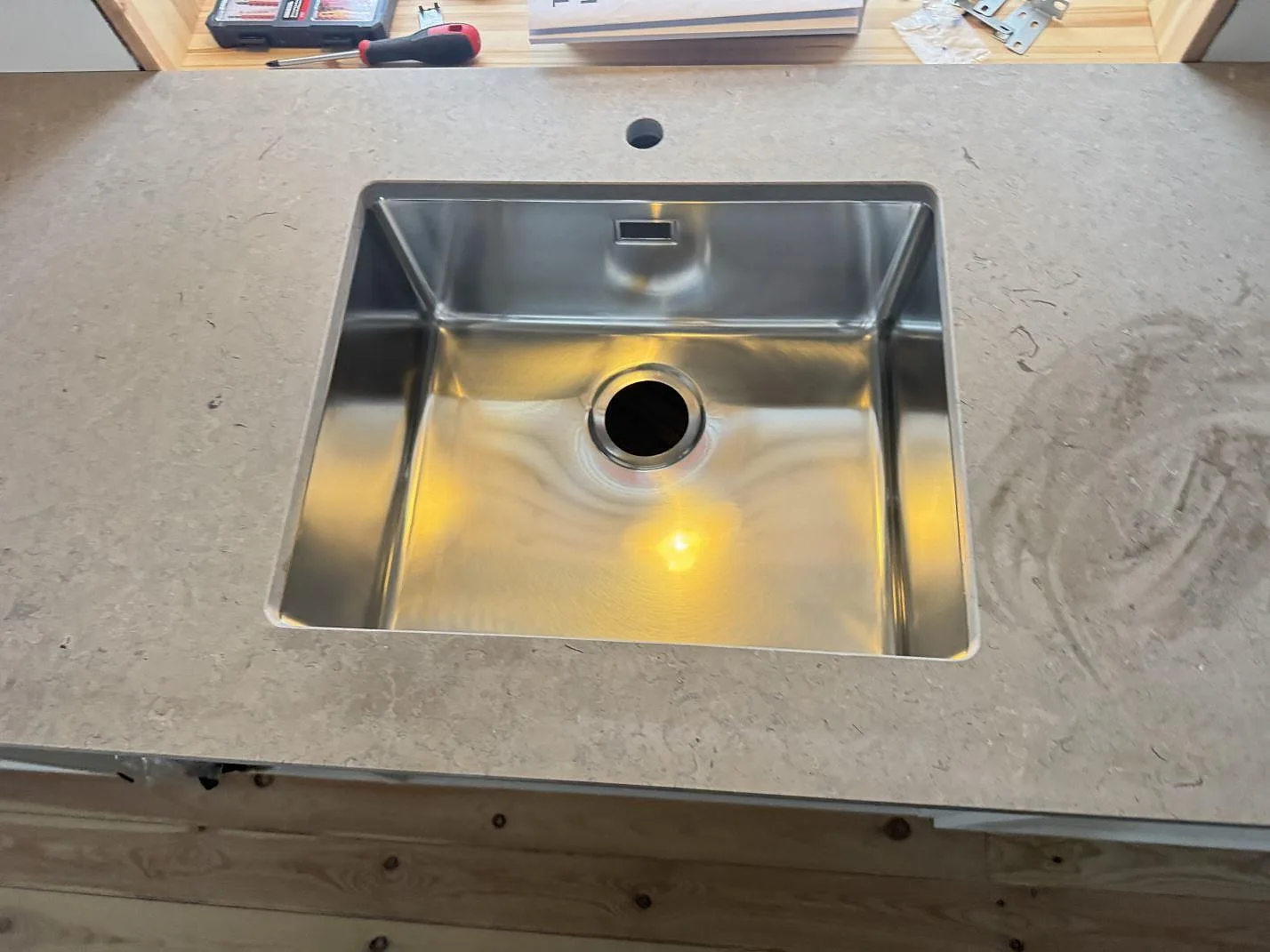 Underlimmad rostfri diskho infälld i en bänkskiva i matt Azul Valverde, sedd ovanifrån, i ett kök i Kristianstad.