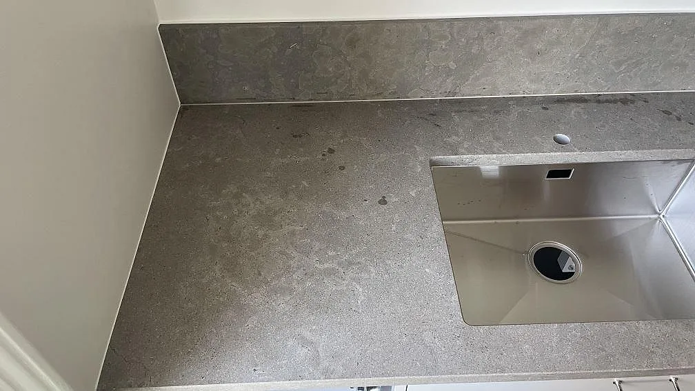 Grå Azul Valverde kalkstensbänk med underlimmad rostfri diskho och bänkskivans matta fossila ådring i ett kök i Malmö.