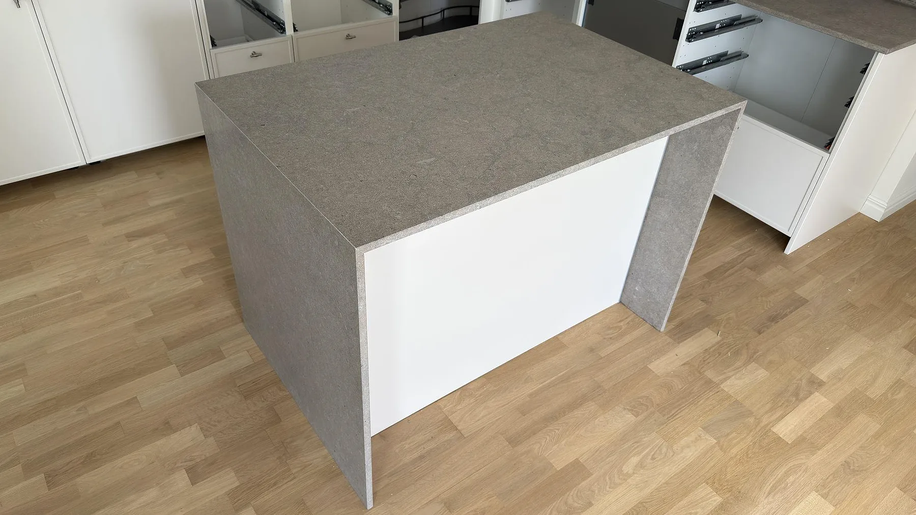 Köksö med matt Azul Valverde marmor som topp och sidor, monterad framför vita köksstommar i Sundbyberg.