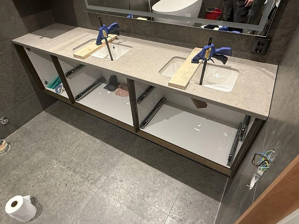 Badrumsbänkskiva i matt Azul Valverde kalksten med två underlimmade vita tvättställ på en dubbelkommod i Västervik.