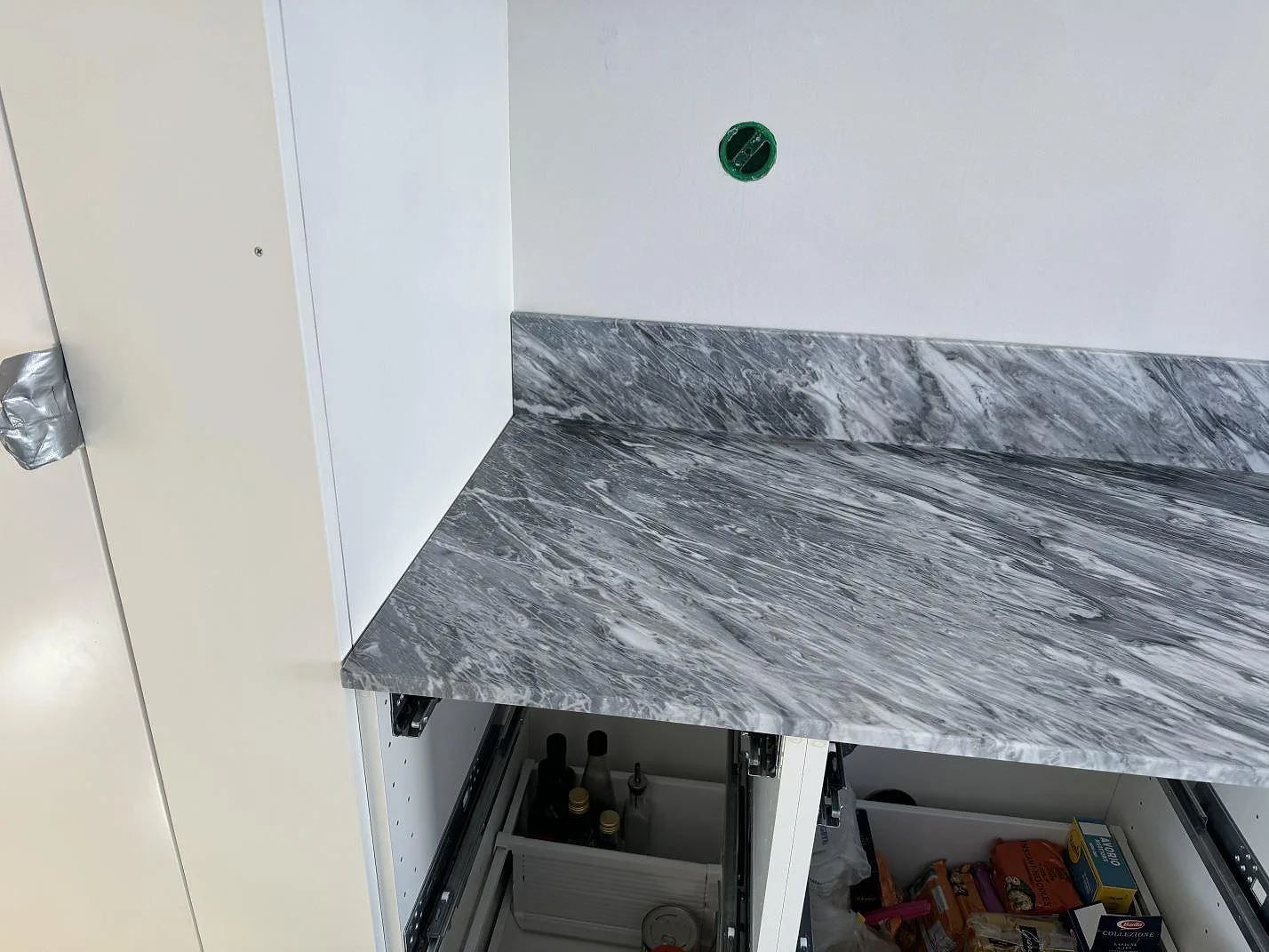 Hörnbänk i matt Bardiglio marmor med uppvikt stänkskydd och öppna köksstommar i Lindome.