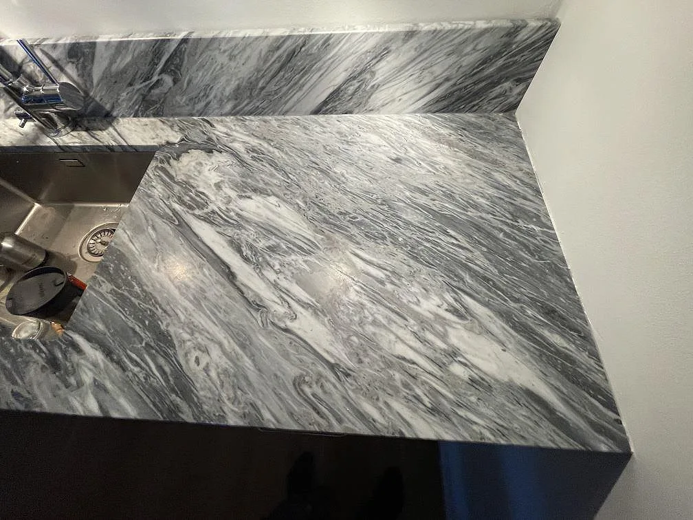 Underlimmad rostfri diskho och blandare i grå Bardiglio marmorbänkskiva med matt yta i ett kök i Stockholm.