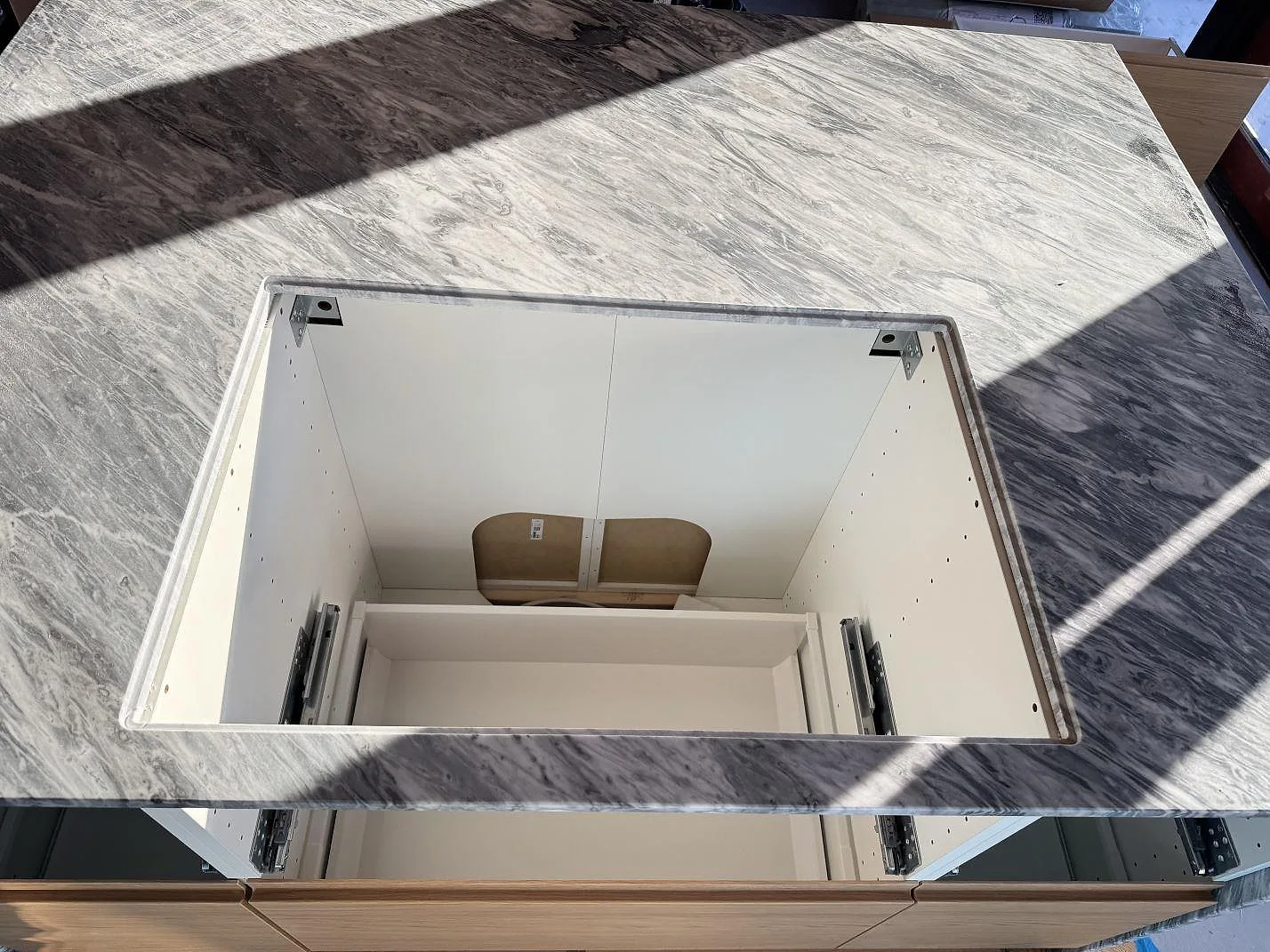 Detalj av stor öppning i en matt Bardiglio köksbänkskiva över vita köksstommar i Tisvilde.