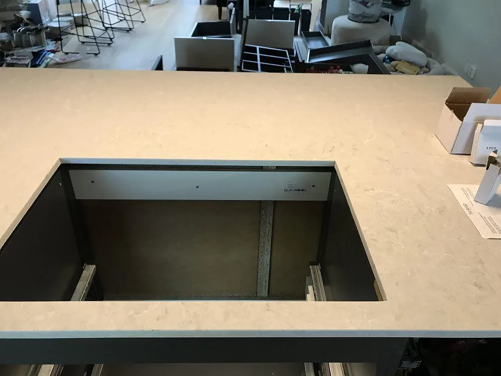 Köksö i Bianco Drift med urtag för häll, polerad kvartskomposit i ett kök i Lomma under montering.
