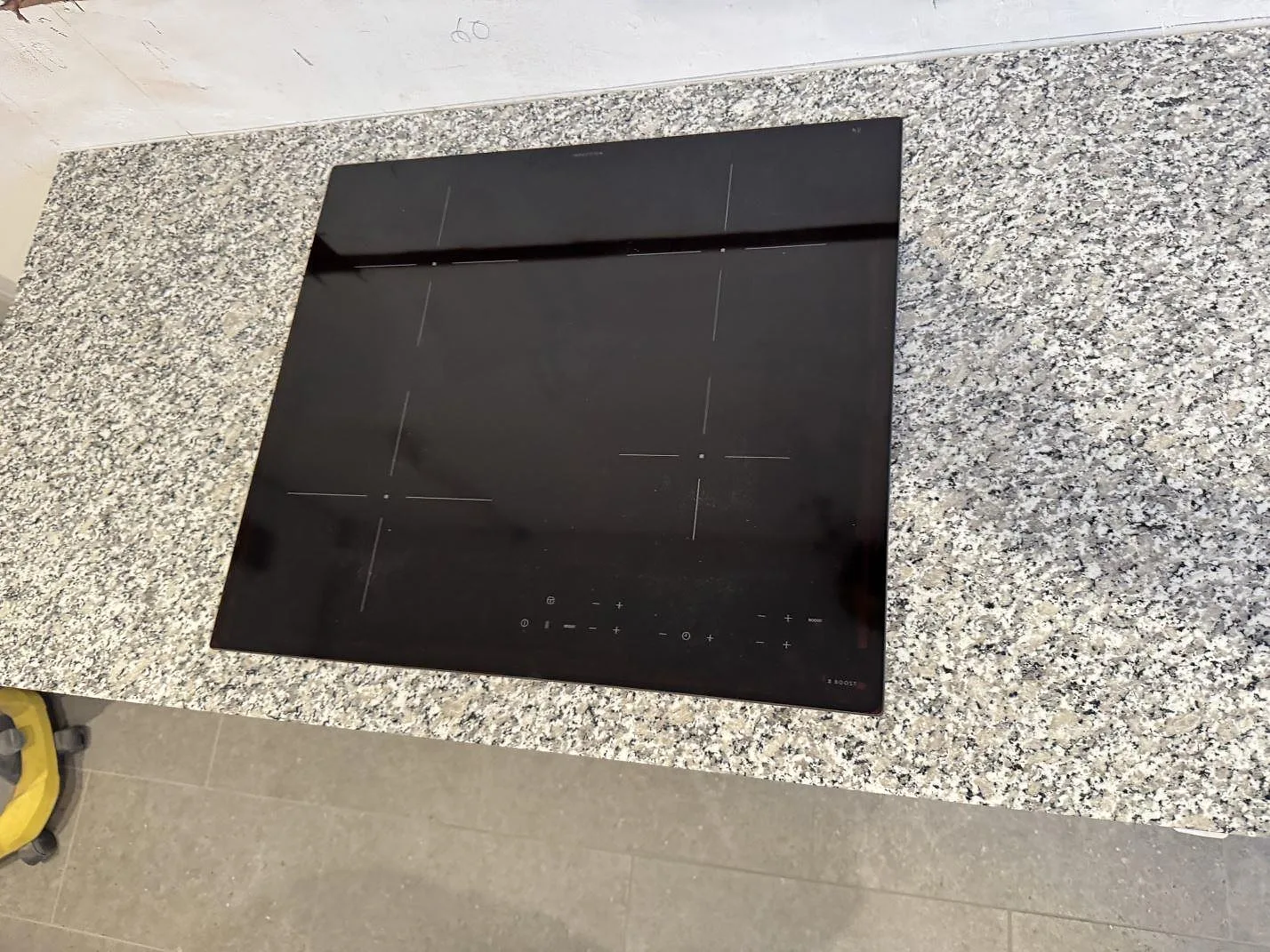 Detalj av svart häll på polerad köksbänkskiva av Bianco Sardo granit i Helsingborg.
