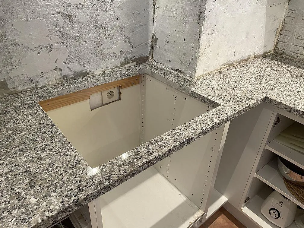 Bianco Sardo granitbänkskiva med hälluttag, låg stenkant och öppen köksstomme under montering i Lund.