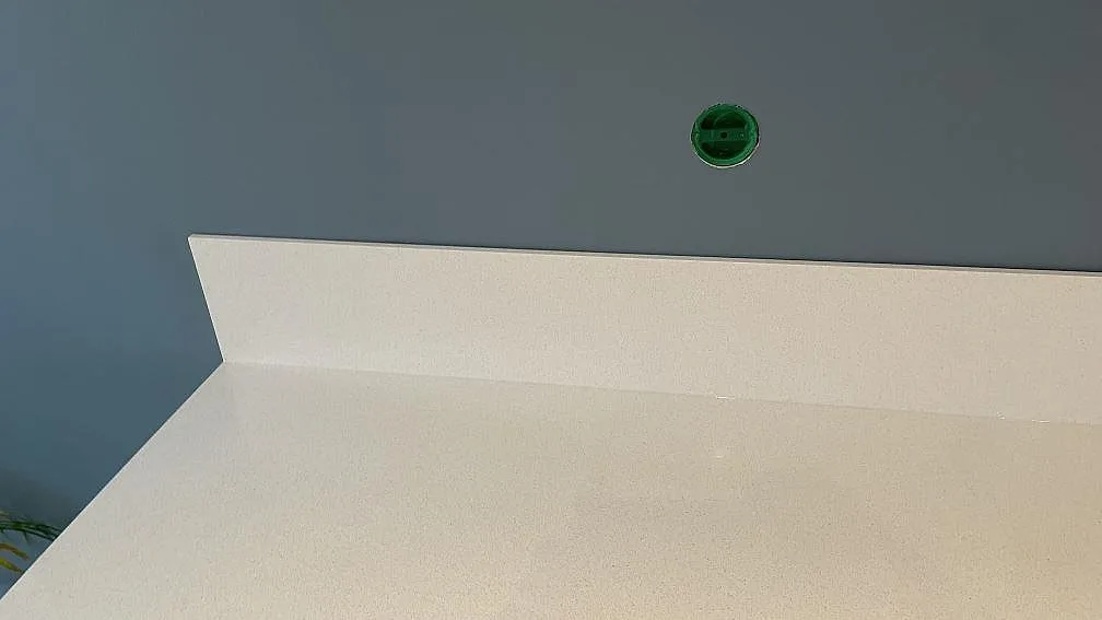 Detalj av uppvikt stänkskydd och polerad Blanco Norte komposit bakom köksbänken i Helsingborg.