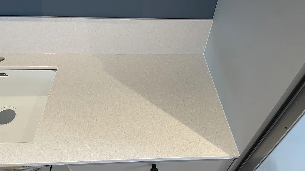 Sidovy av diskho och ljus Blanco Norte köksbänkskiva i polerad komposit vid vägg i Helsingborg.
