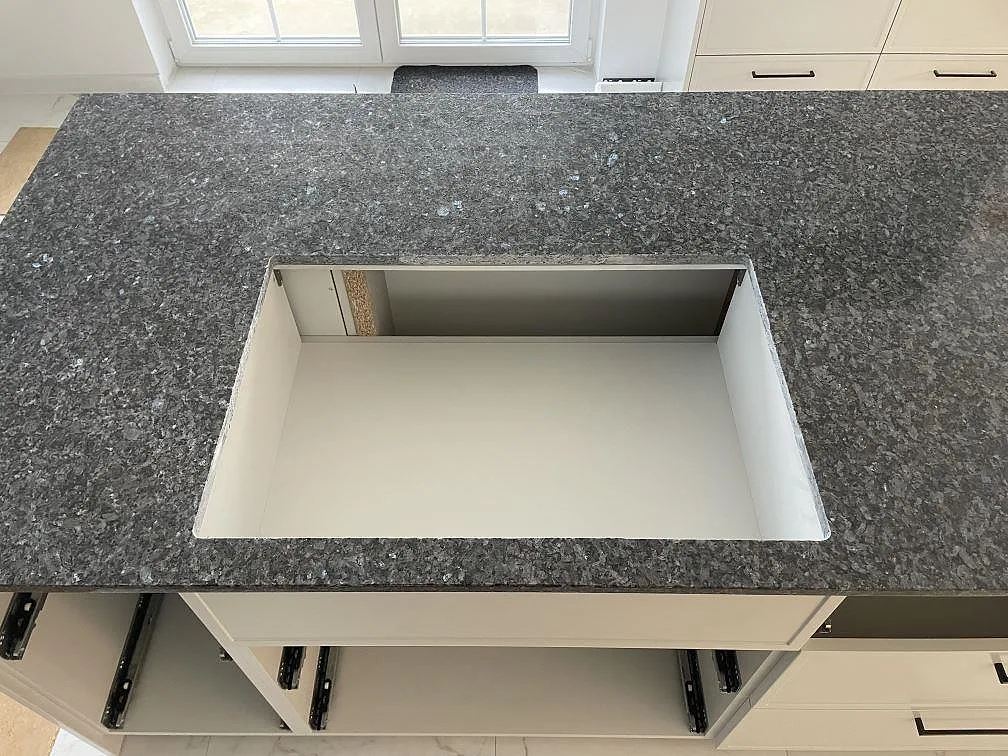 Topvy av köksö med köksbänkskiva i polerad Blue Pearl granit och stort rektangulärt urtag i Sölvesborg.