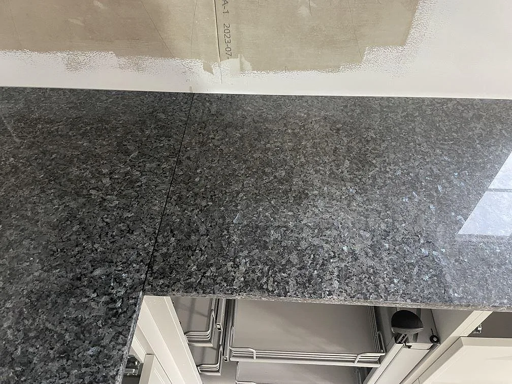 Närbild av skarv och blank yta i polerad Blue Pearl granit på köksbänkskiva i Sölvesborg.