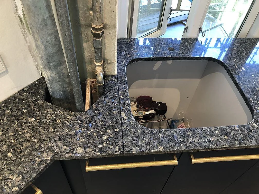 Underlimmad diskho i polerad Blue Pearl granitbänkskiva, sett ovanifrån under montering i ett kök i Valby.