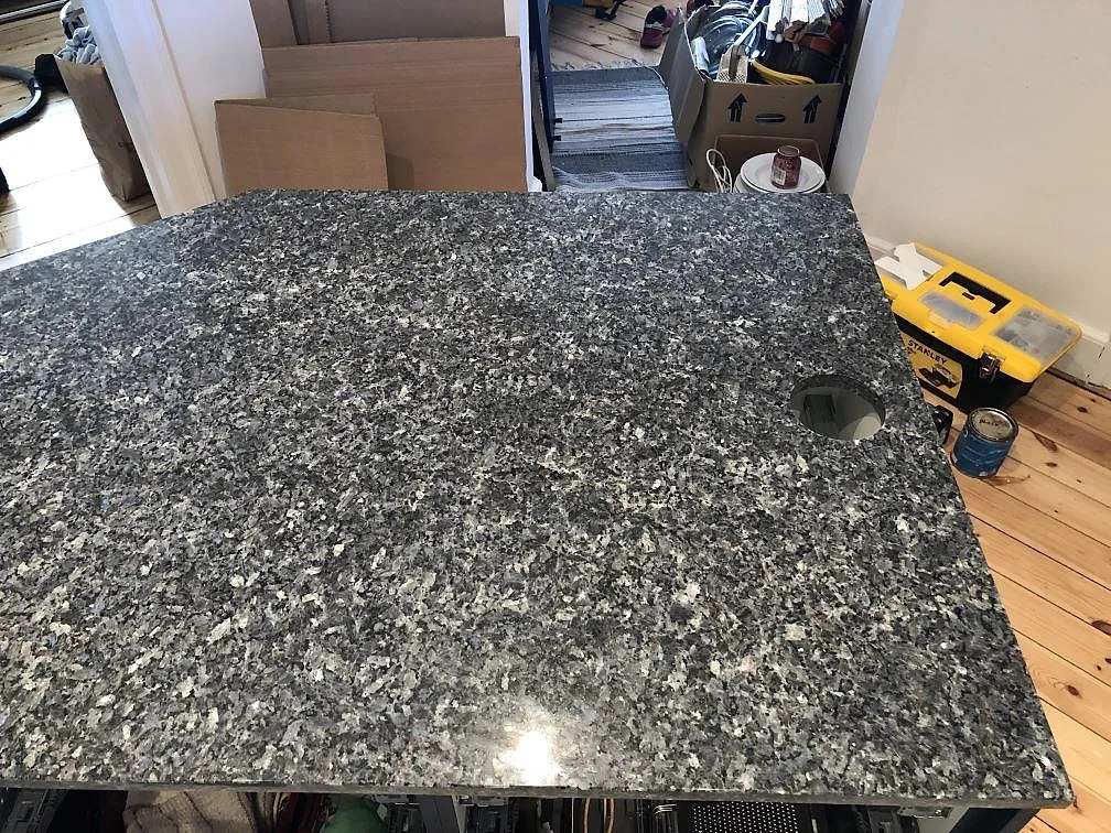 Närbild på den skimrande blågrå ytan i polerad Blue Pearl granitbänkskiva i ett kök i Valby.