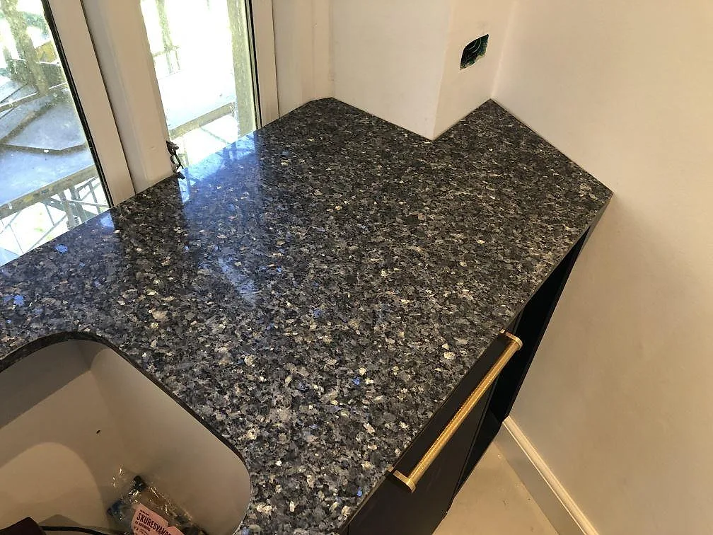 Vinklad polerad Blue Pearl granitbänkskiva med djupa blågrå reflexer i ett kök i Valby.