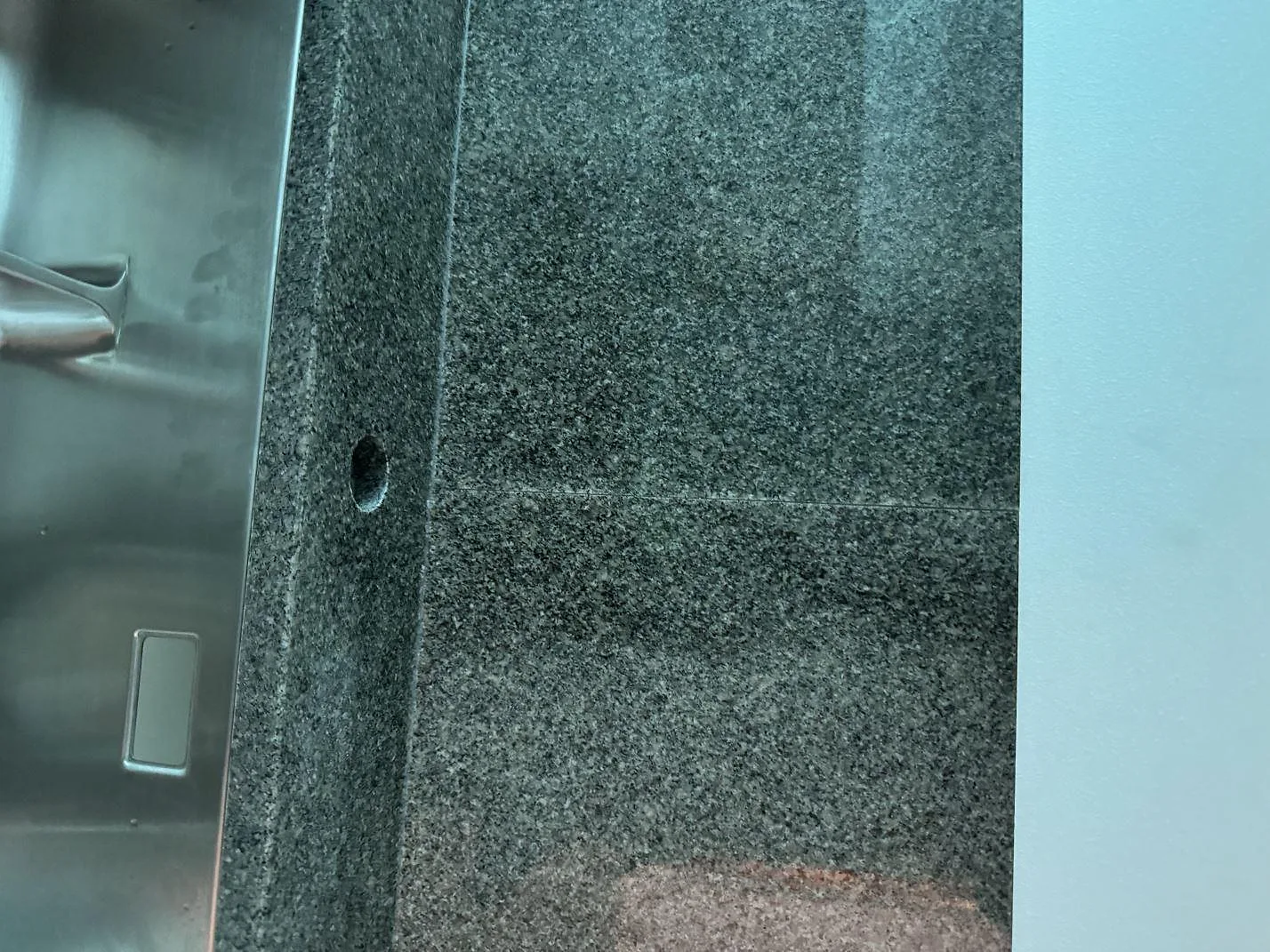 Detaljbild av polerad Bohus Grå granit vid diskhon och stänkskyddet i köket i Ängelholm.