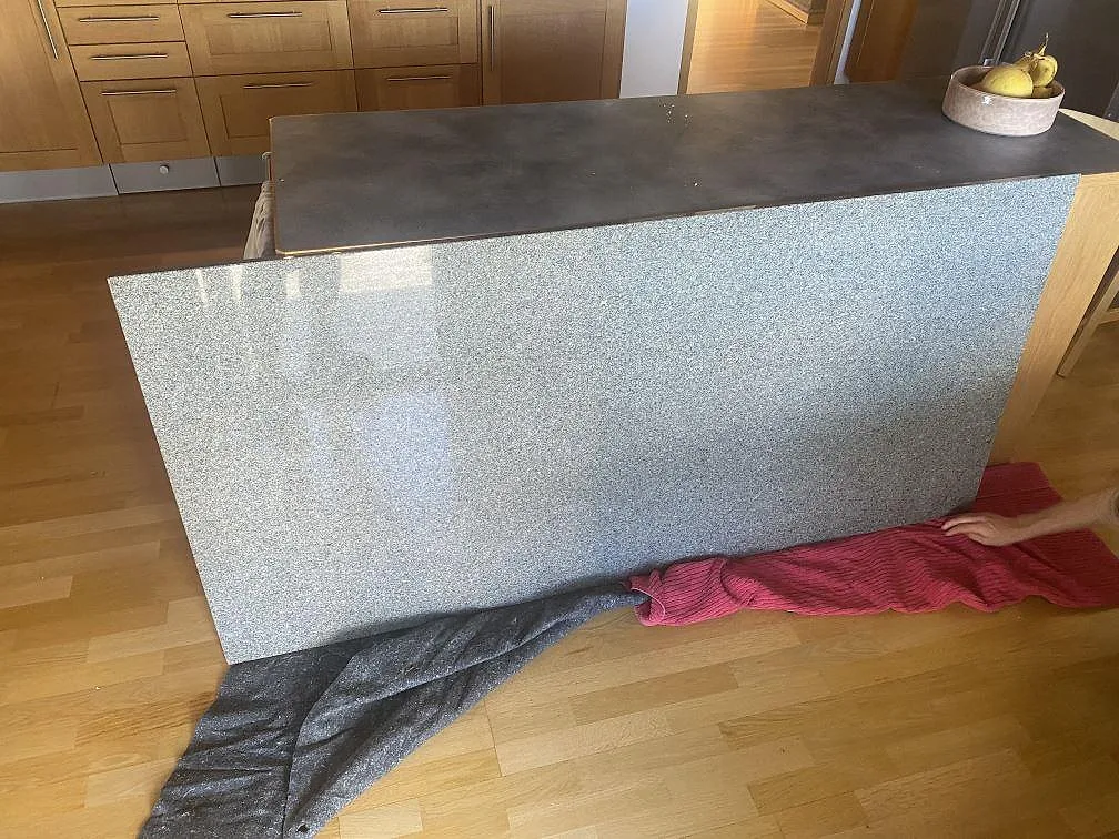 Köksbänkskiva i polerad Bohus Grå granit på en fristående köksö med spräcklig grå yta i ett kök i Askim.