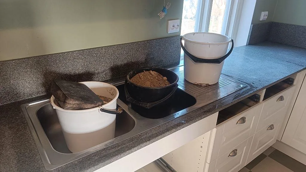 Bohus Grå granit som köksbänkskiva med diskbänkszon, hällzon och uppvikt stänkkant under montering i Brantevik.