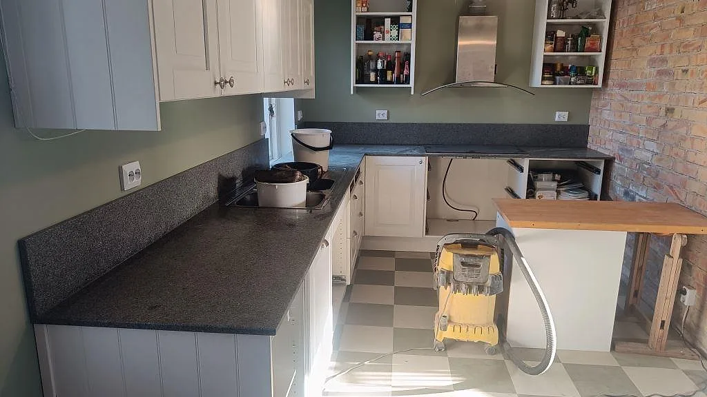 L-formad köksbänkskiva i Bohus Grå granit, 20 mm, med blandad matt och polerad finish i ett kök i Brantevik.