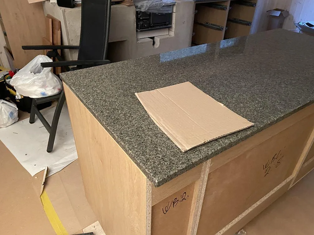 Polerad Bohus Grå granit på köksö med trästommar och skyddskartong under montering i Dannike.