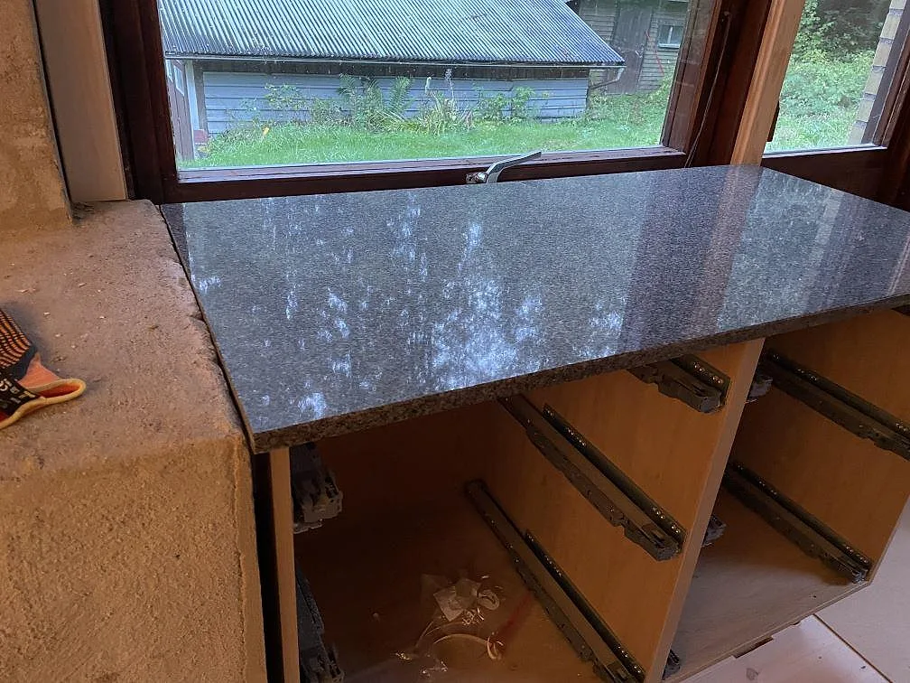 Polerad Bohus Grå granitskiva monterad vid fönster över öppna trästommar i Dannike.