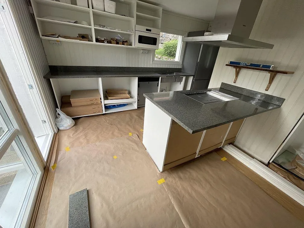 Köksbänkskiva i Bohus Grå granit, polerad, med halvö och väggbänkar i ett kök under montering i Göteborg.