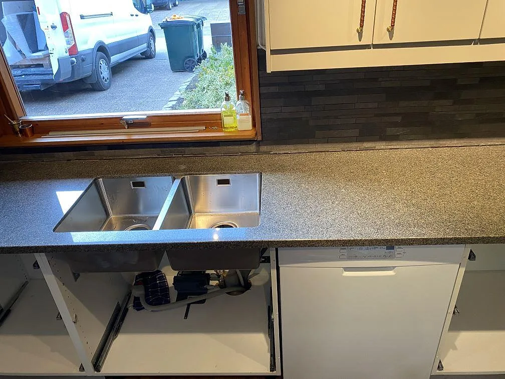 Polerad Bohus Grå granitbänkskiva med rostfri dubbelho under fönster och ljusa skåp i kök i Höör.