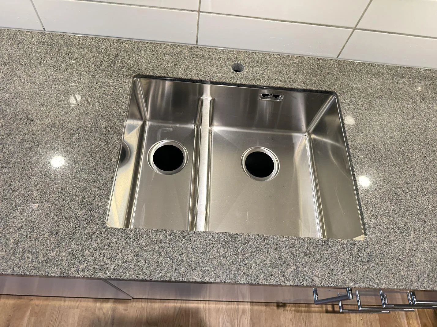 Detalj av rostfri dubbelho infogad i köksbänkskiva av polerad Bohus Grå granit i Kyrkesund.