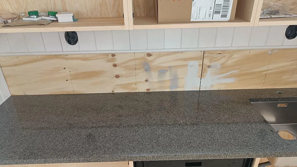 Detalj av polerad Bohus Grå granitbänkskiva vid diskhozonen och vit kakelvägg i Landsbro.