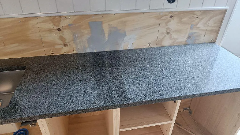 Polerad Bohus Grå granitbänkskiva med tät grå kornighet över träinredning i ett kök i Landsbro.