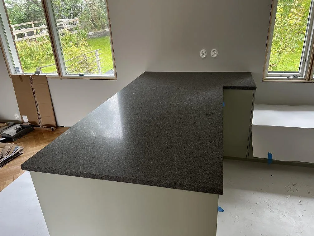Halvö med köksbänkskiva i matt Bohus Grå granit i ett kök under montering i Lerum.