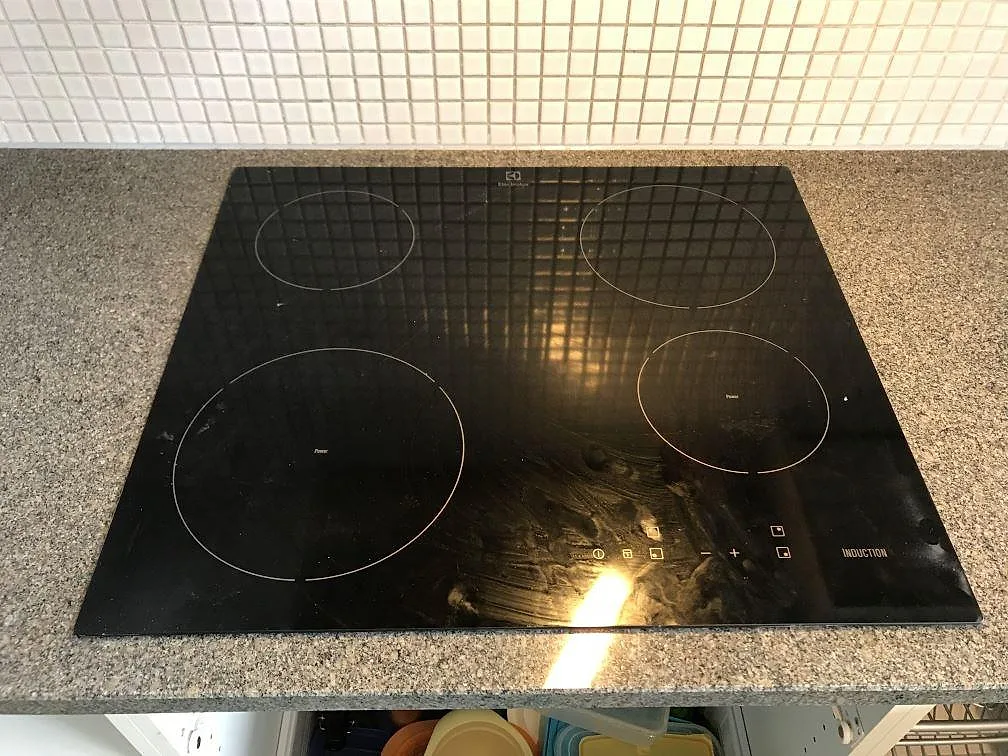 Polerad Bohus Grå granitbänkskiva med synlig fältspats- och kvartskornighet och vitt kakelstänkskydd i ett kök i Malmö.