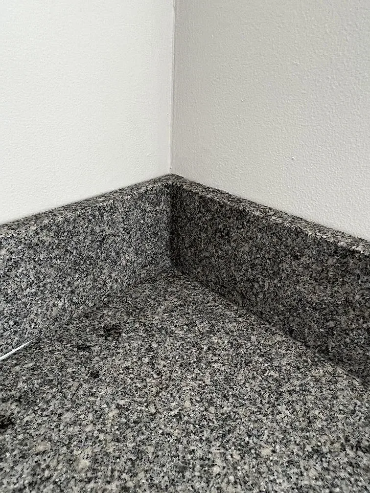 Närbild av hörn med matt Bohus Grå granit, hög stänkkant och gråsvart mineralmönster i Malmö.