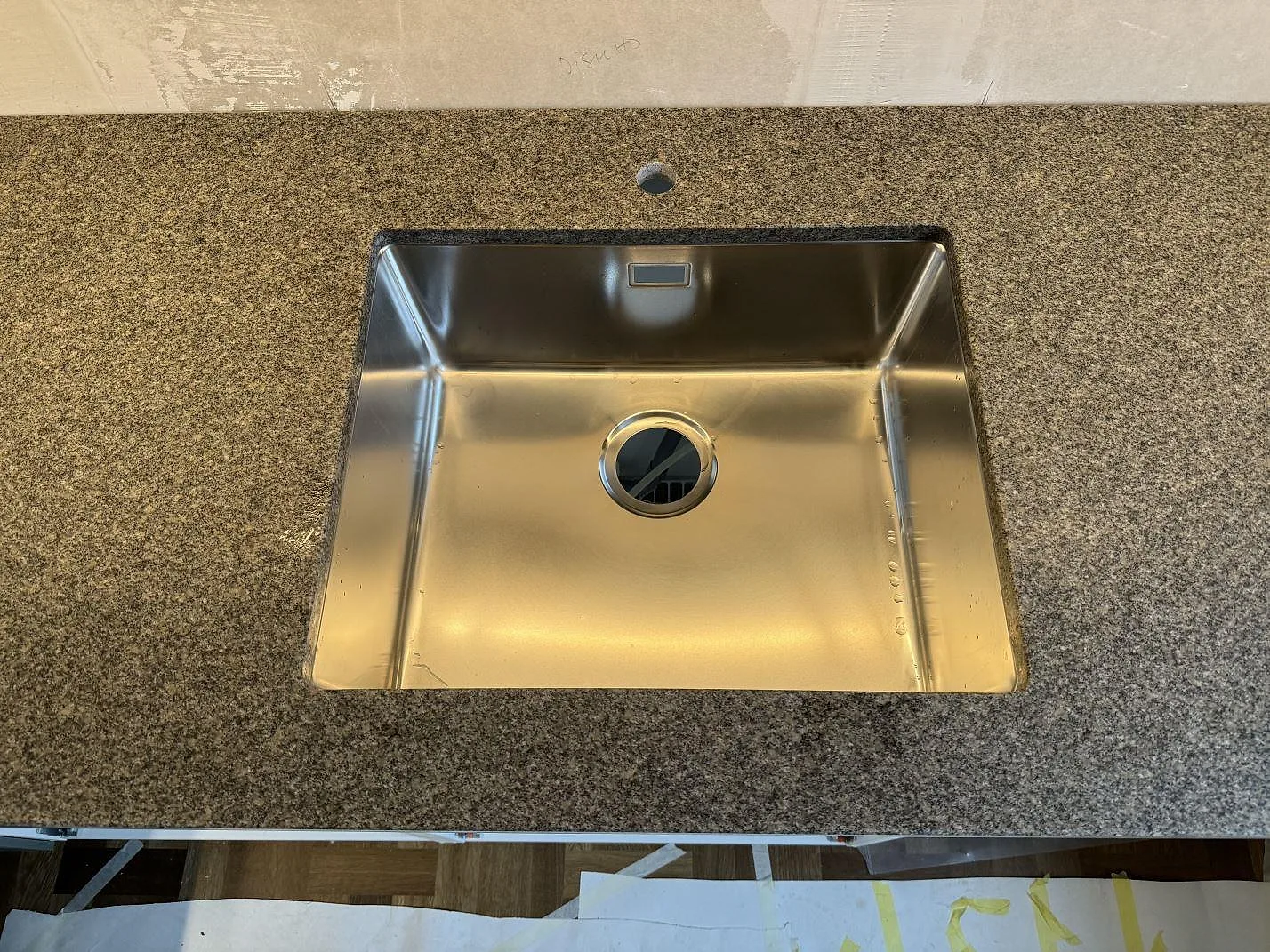 Närbild på underlimmad rostfri diskho i matt Bohus Grå granit med blandarhål i ett kök i Malmö.