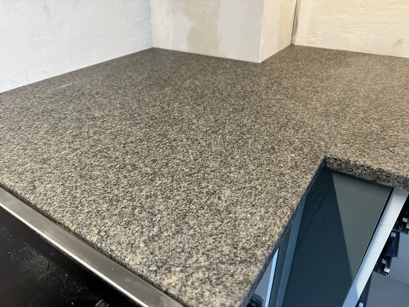 Detalj av matt Bohus Grå granit runt L-hörn med separat spis intill i ett kök i Malmö.