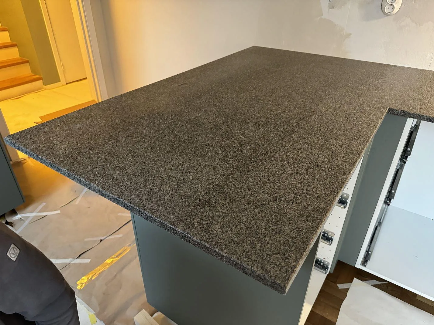 Bred halvö i matt Bohus Grå granit monterad på grå köksstomme i ett kök under arbete i Malmö.