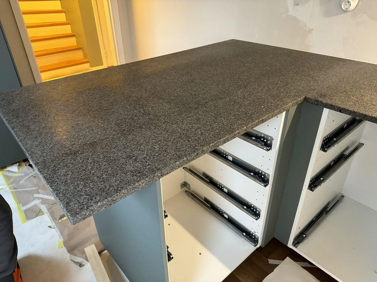 Halvö i matt Bohus Grå granit med synlig grå kornstruktur och öppna köksstommar under montering i Malmö.