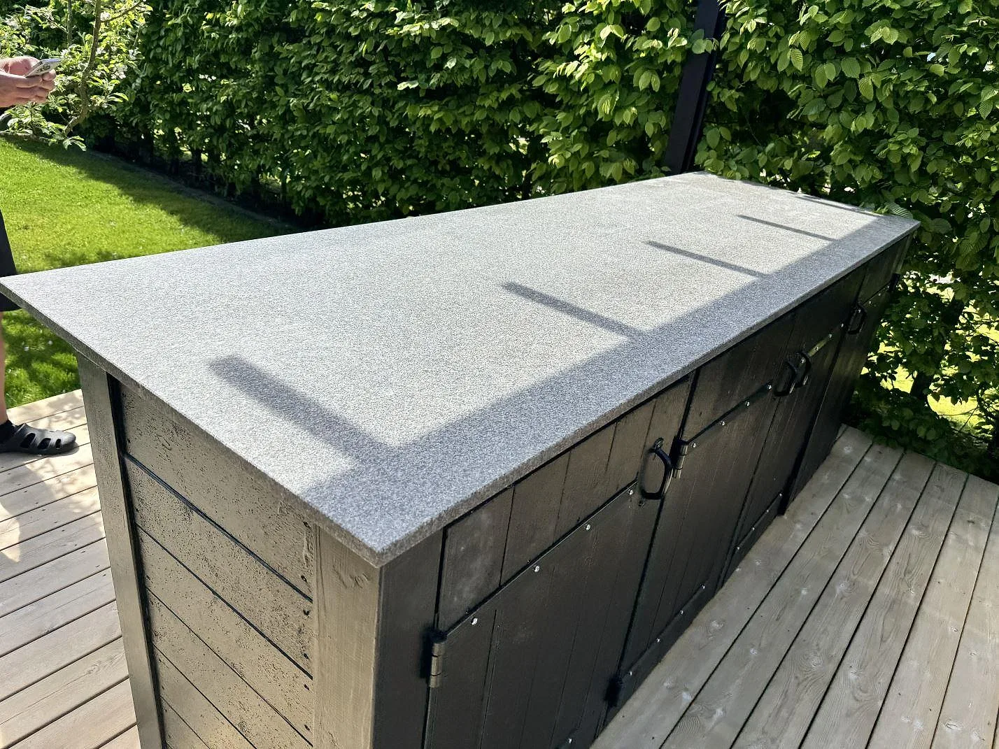 Detalj av jämnkornig matt Bohus Grå granit som arbetsyta på ett utekök på trädäck i Malmö.