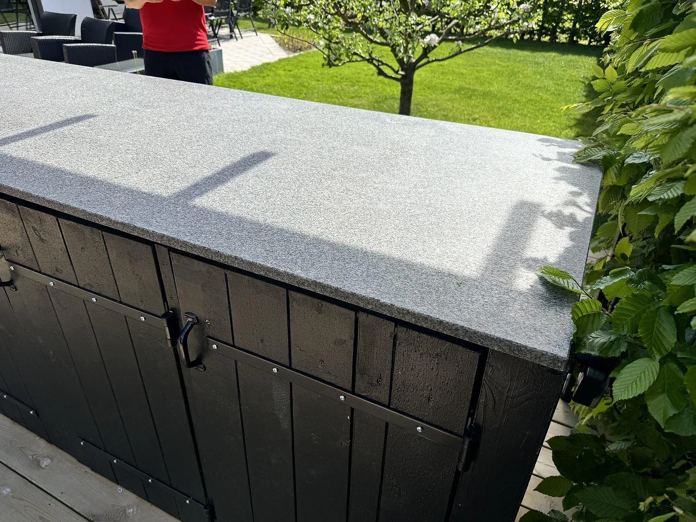 Sidovy av matt Bohus Grå granit monterad som köksbänkskiva på mörk träinredning i ett utekök i Malmö.