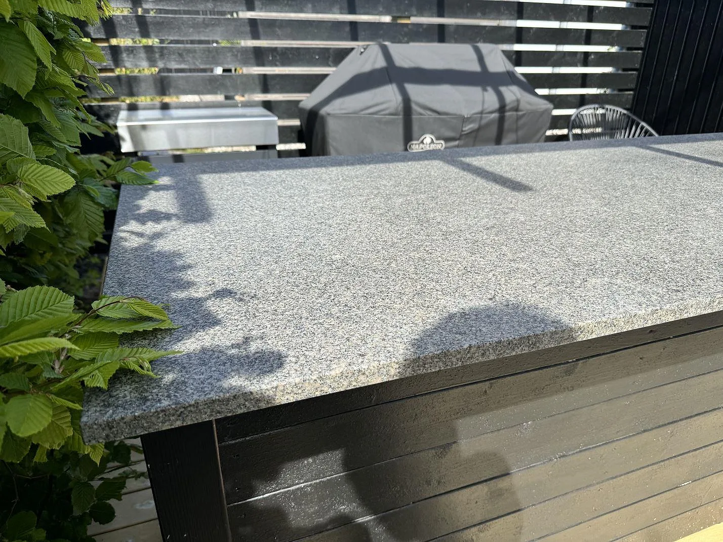 Närbild på den grå, matta Bohus Grå granitytan i ett utekök med trädäck och grillmiljö i Malmö.