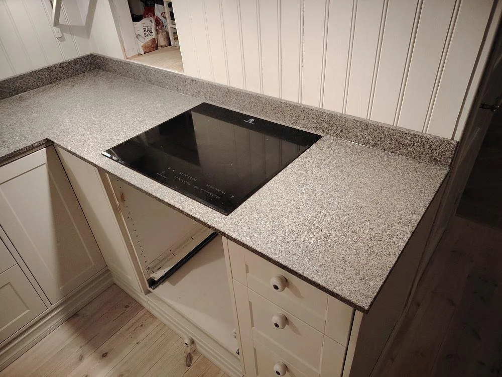 Matt Bohus Grå granit runt en installerad häll med uppvikt stänkkant i köket i Mockfjärd.