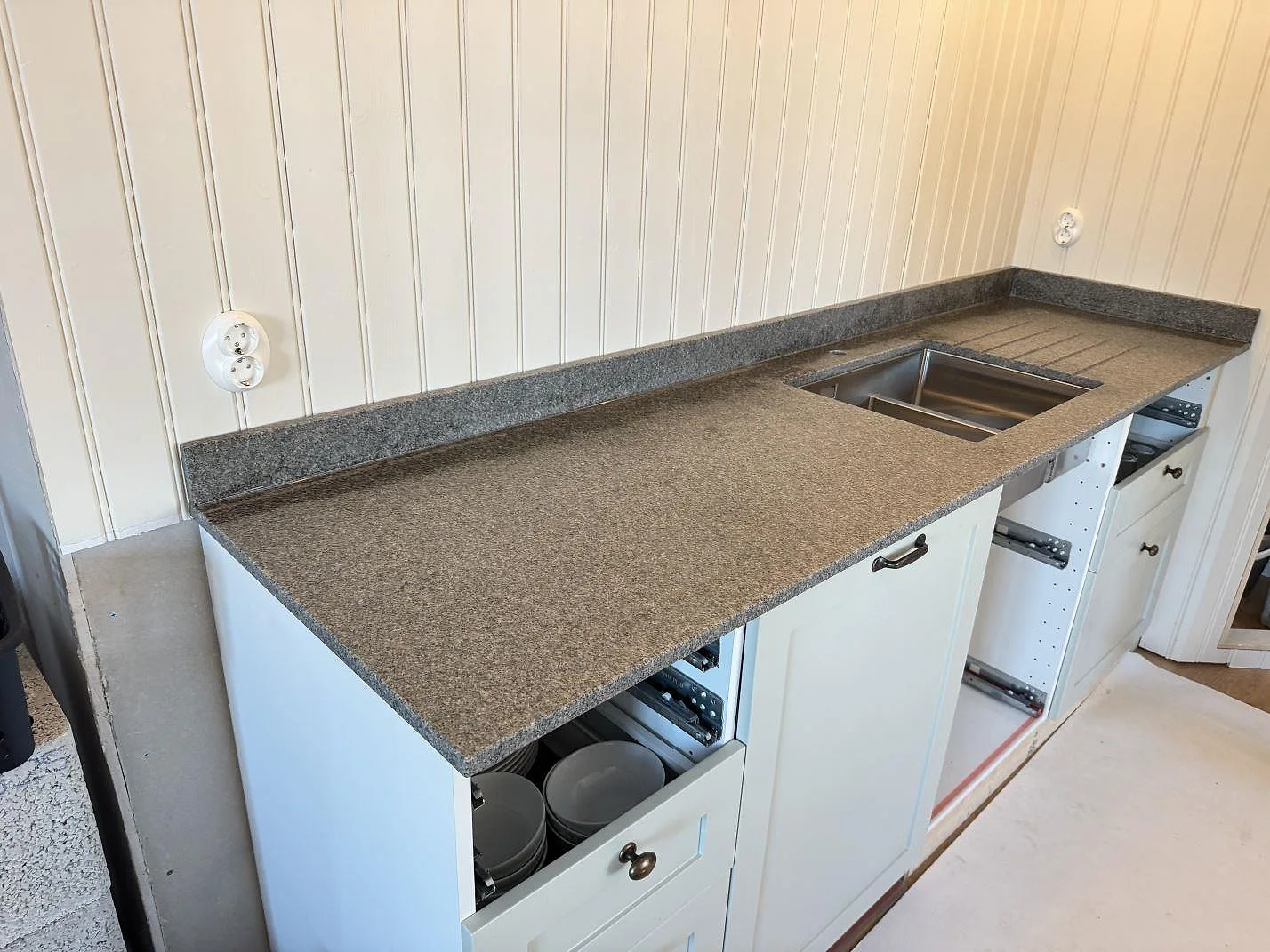 Köksbänkskiva i Bohus Grå granit, matt yta, med underlimmad rostfri diskho i ett kustnära kök i Slöinge under montering.