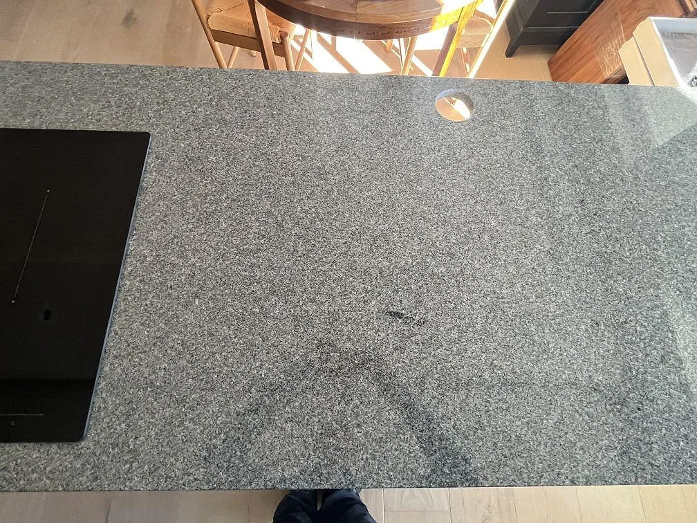Detalj av polerad Bohus Grå granit på köksö med hällkant och rund håltagning i Stockholm.